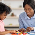 Adorable little black girl and teacher playing with play dough